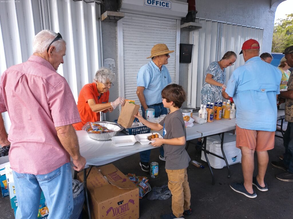 Picture of the food line showing a young boy receiving his snack bag to go with his dinner.